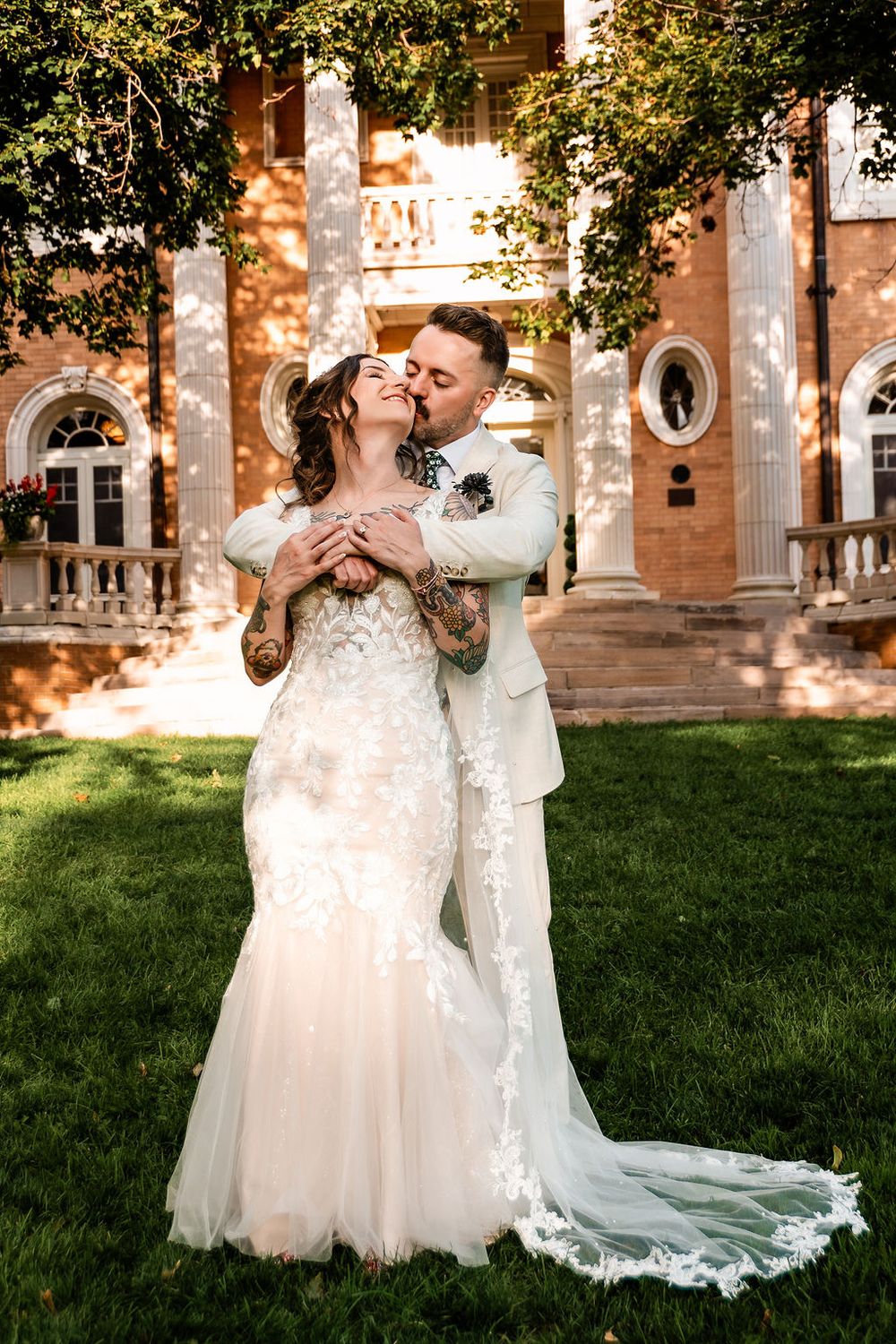 husband holding his wife from behind and kissing her in the grant Humphreys mansion courtyard