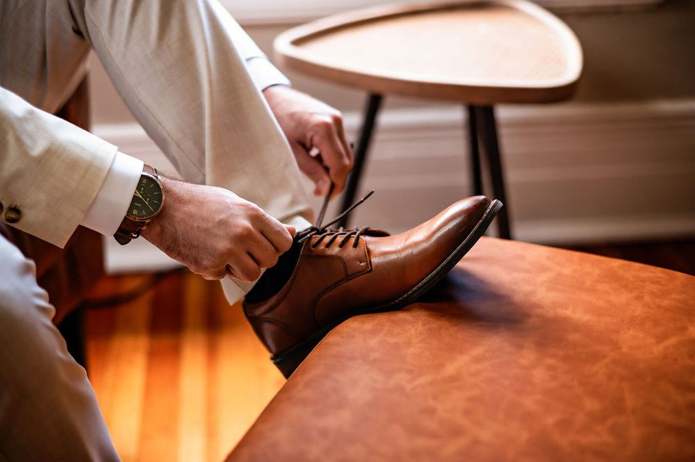 detail shot of a groom tying his wedding shoes
