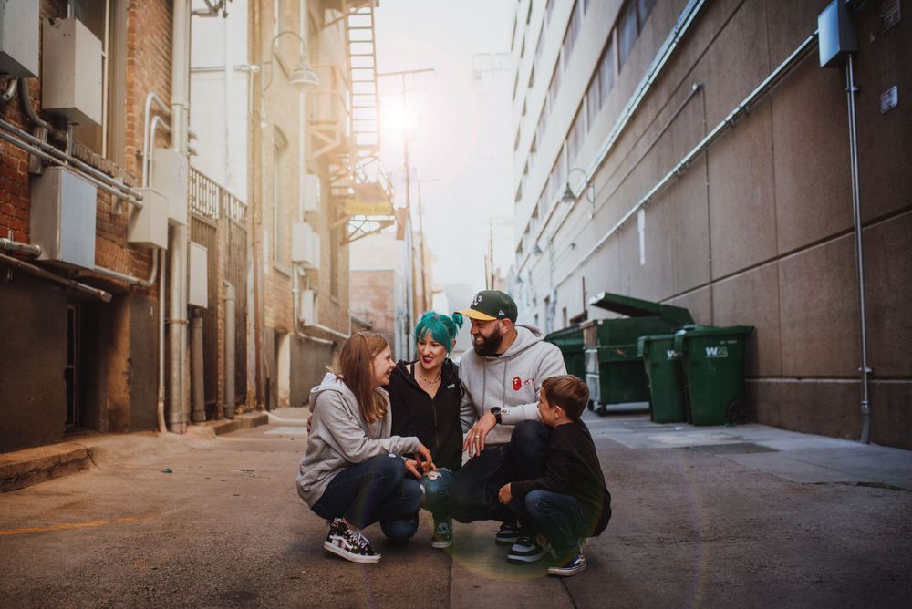 Candid urban family photo – family of four laughing together in a downtown Reno alleyway, with sunset light and city textures.