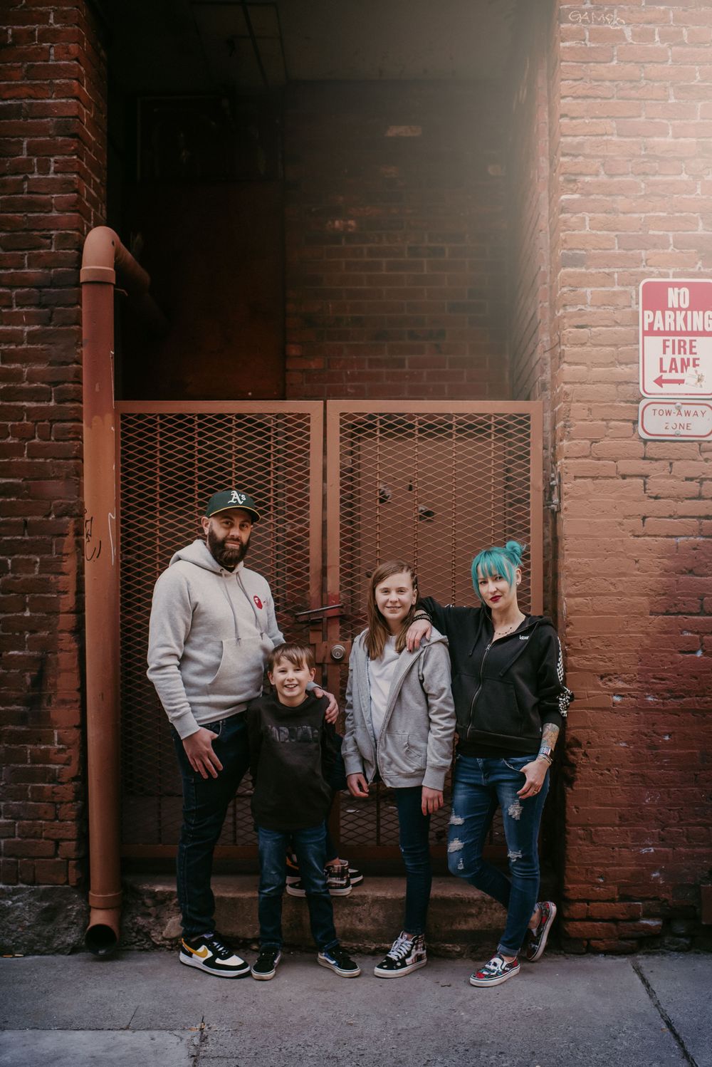Urban family portrait session – stylish family of four posing in an alley with brick walls and industrial vibes in downtown Reno.
