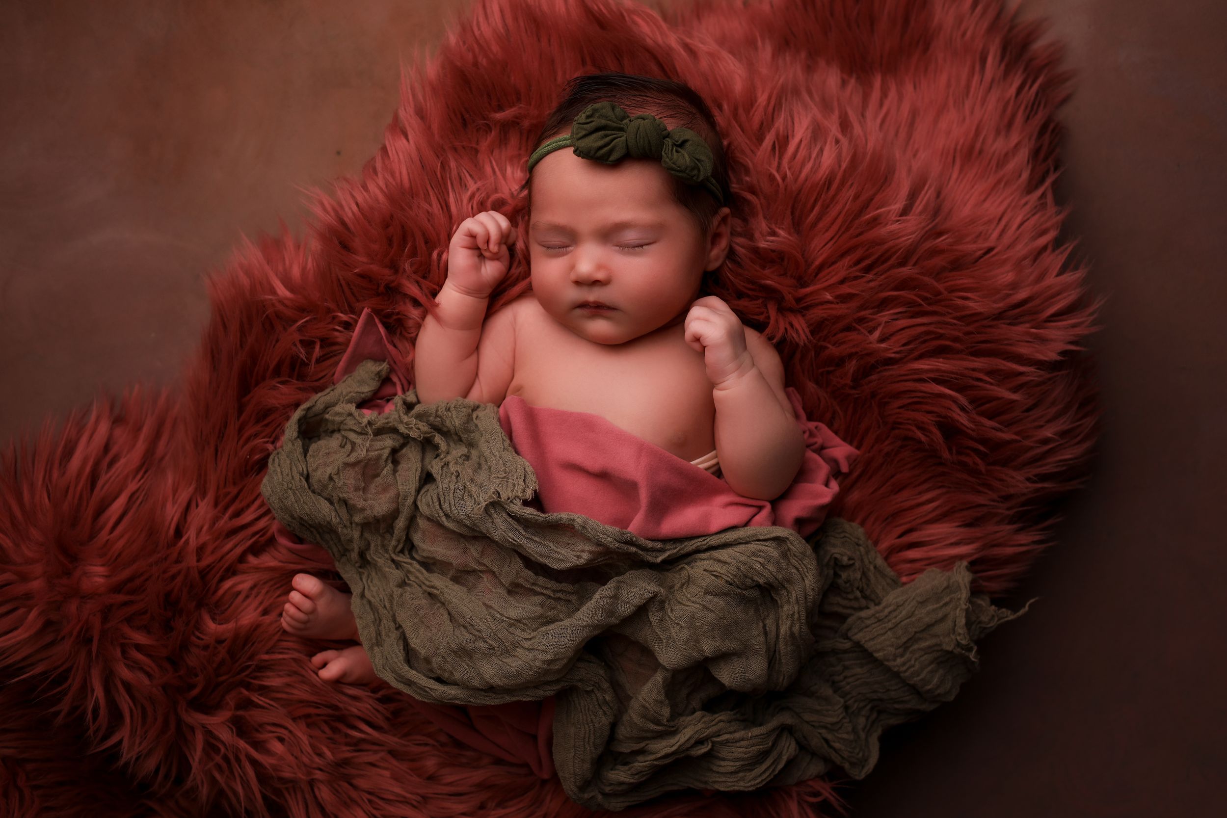 Newborn Baby asleep in pink fur with a green wrap in the studio in Portsmouth New Hampshire.