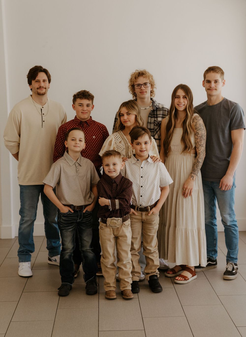 Family group photo showing multiple generations wearing coordinated casual outfits against a white background.