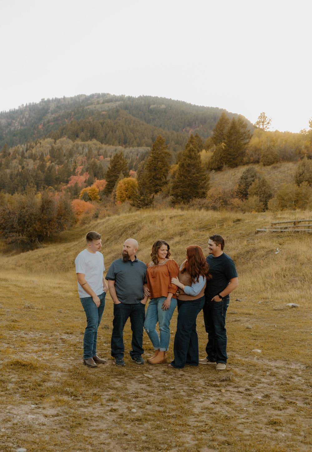 Group photo session in an open field with mountains and fall foliage in the background.