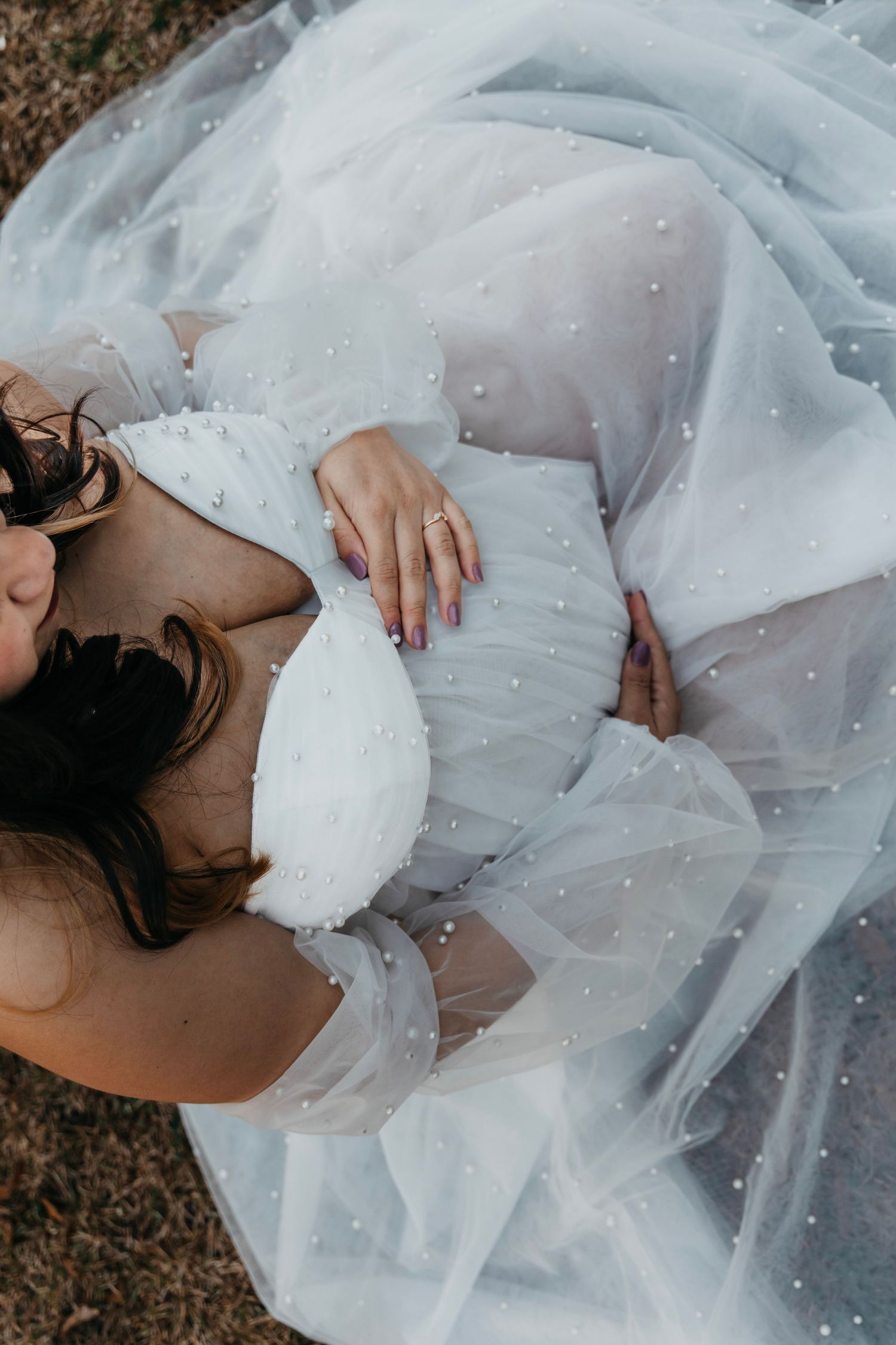 Ethereal bridal photo with flowing white tulle dress against natural background.