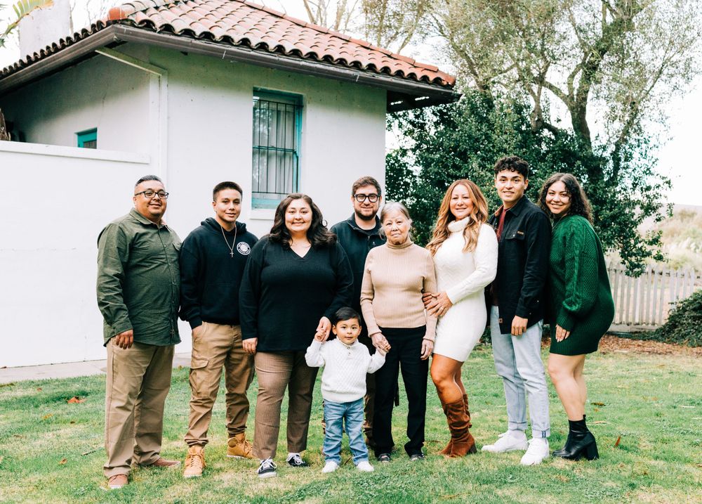 Family of 9 lined up in a straight line in front of a Spanish style house, Casmalia, CA