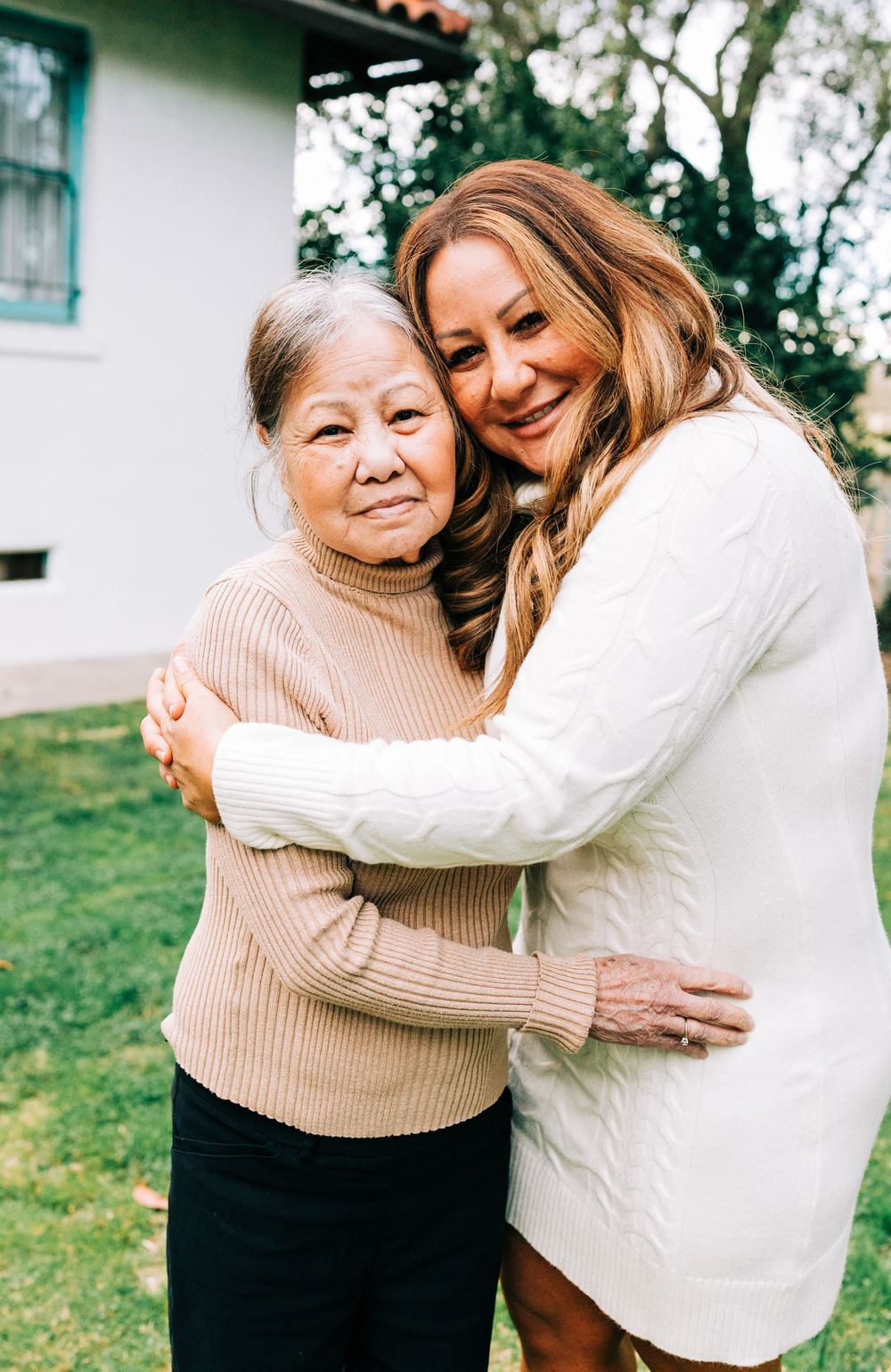 Mom and daughter embracing in front of house, Casmalia, CA