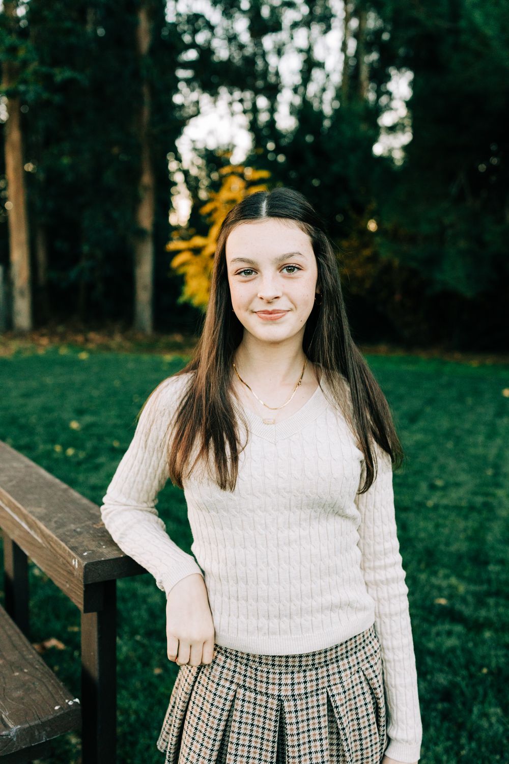 Young girl leaning against deck at sunset in front of tall trees, San Luis Obispo, CA
