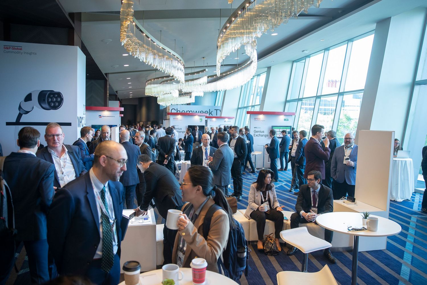 Modern conference venue with floor-to-ceiling windows and mingling attendees.