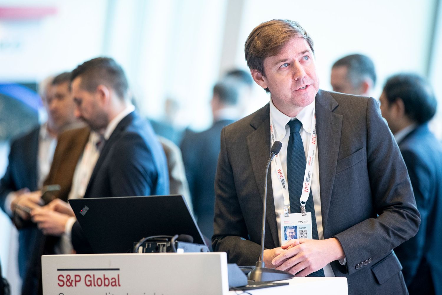 Business professionals seated at conference tables with S&P Global branding visible.