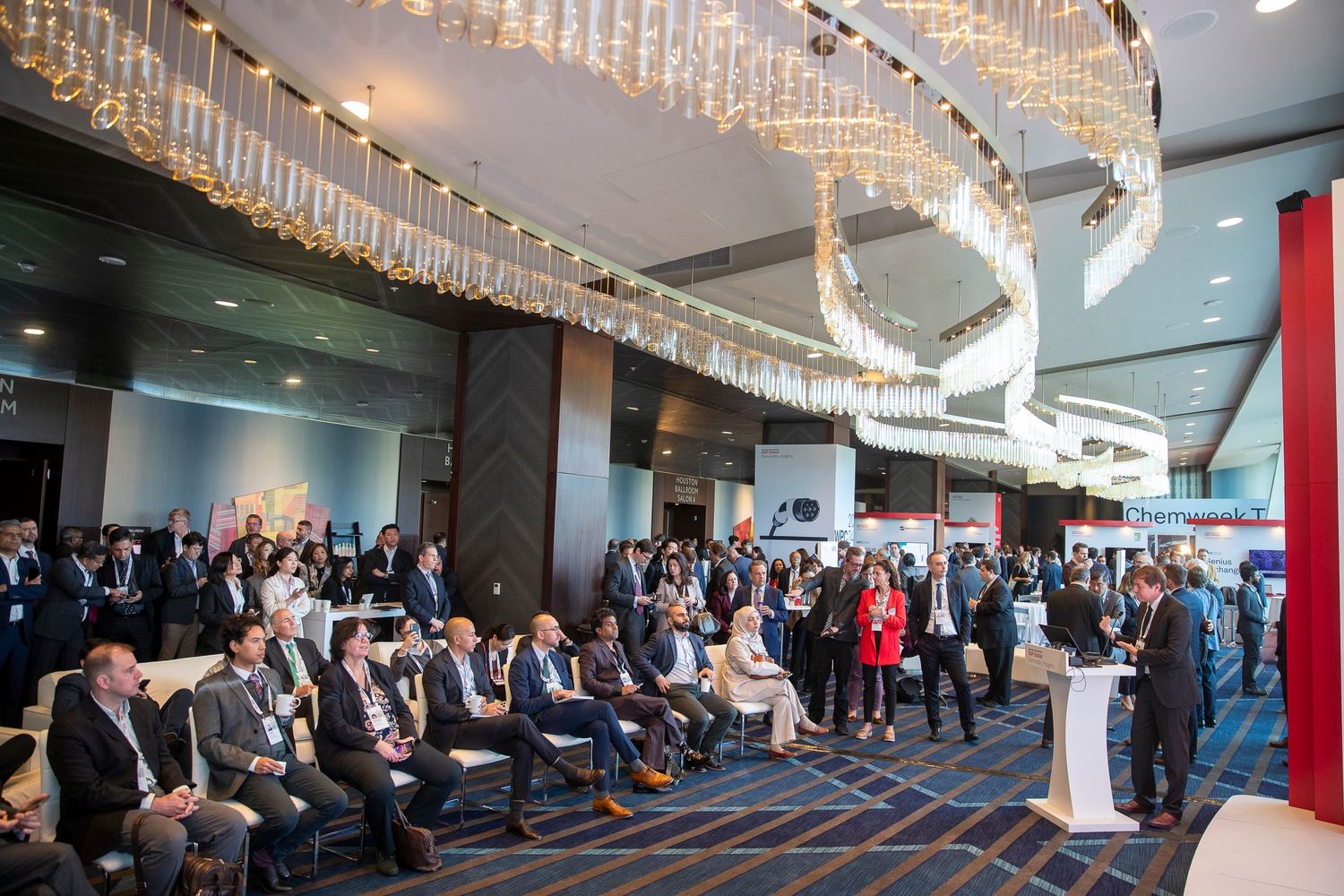 Elegant conference hall with crystal chandeliers and attendees networking.