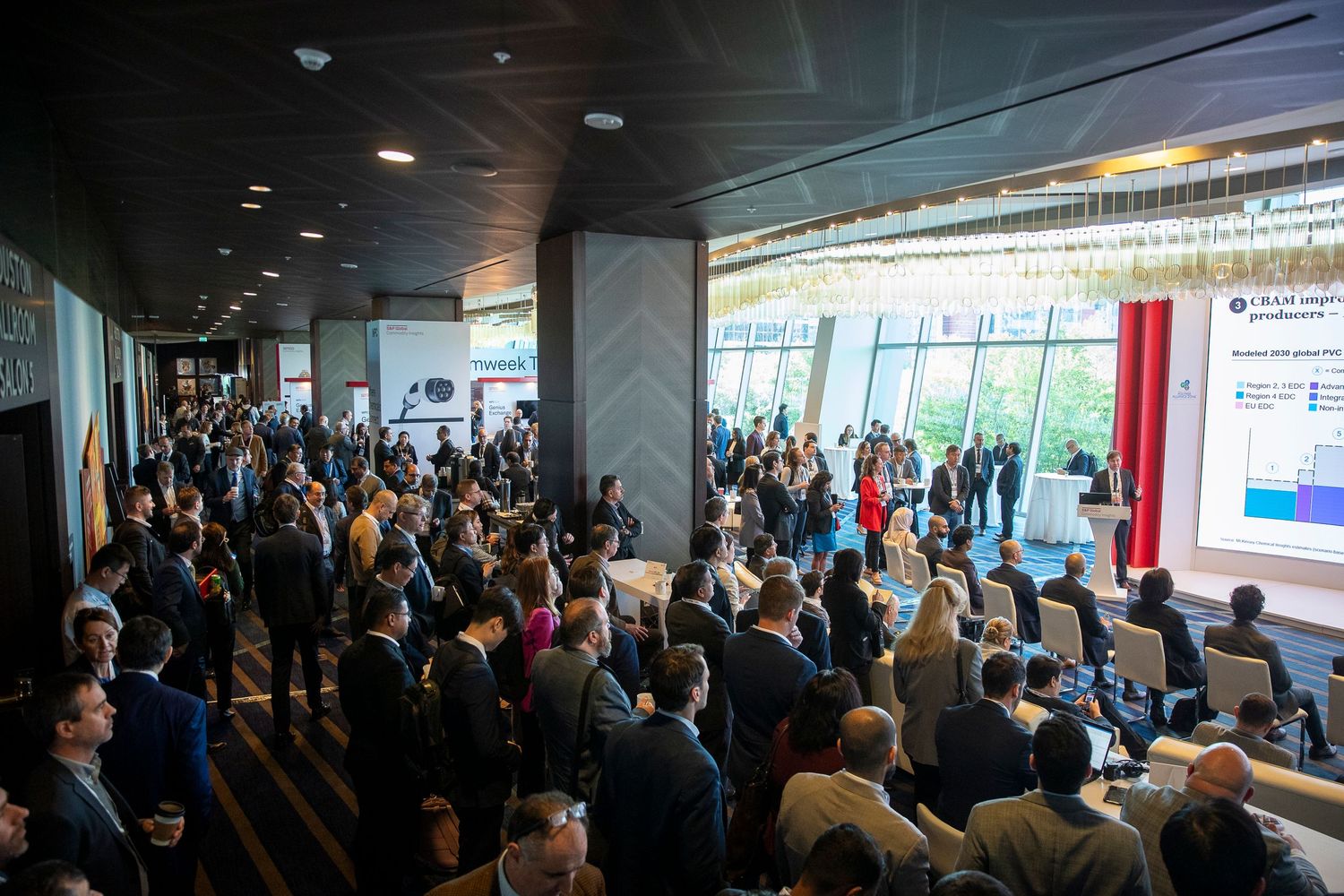 Wide shot of a packed conference room with attendees watching a presentation.