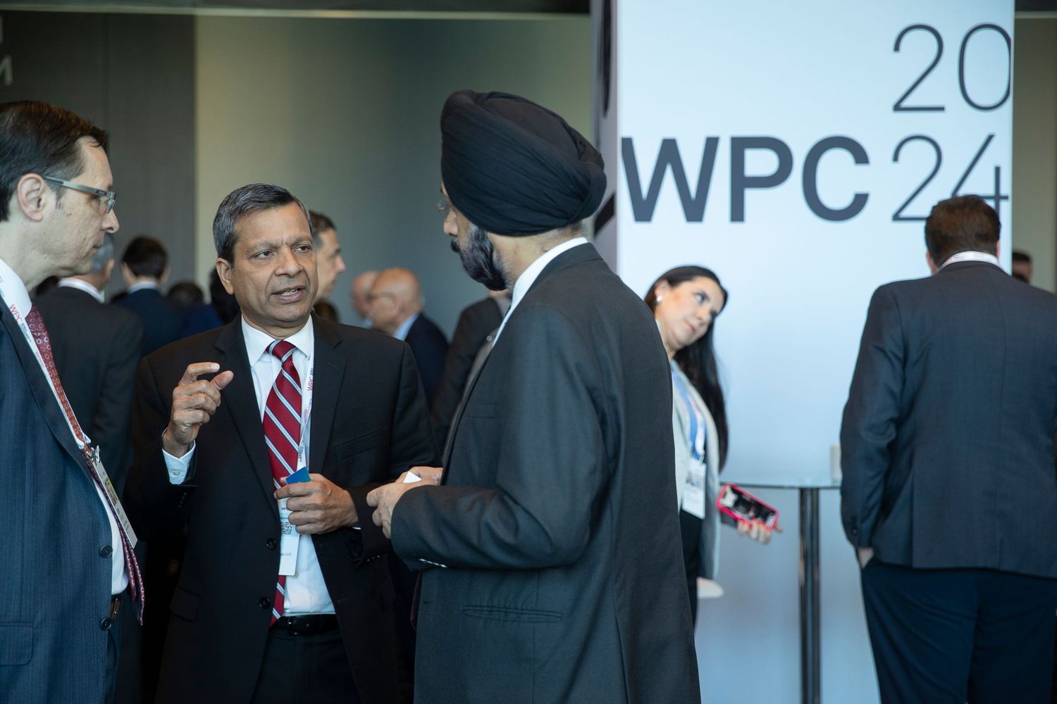 Corporate event space with WPC24 branding and networking professionals.