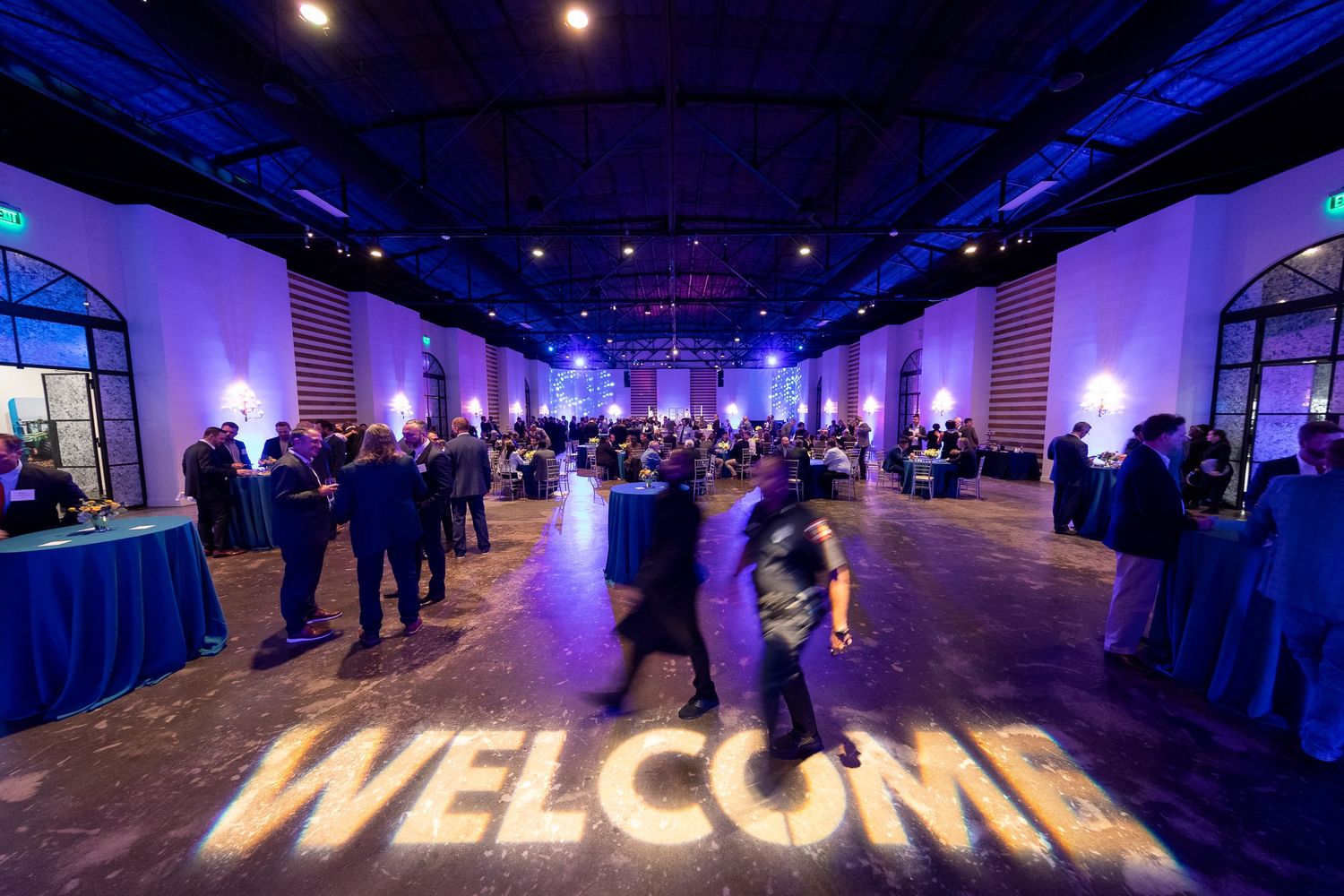 Large event venue with blue lighting and illuminated welcome sign on wall.