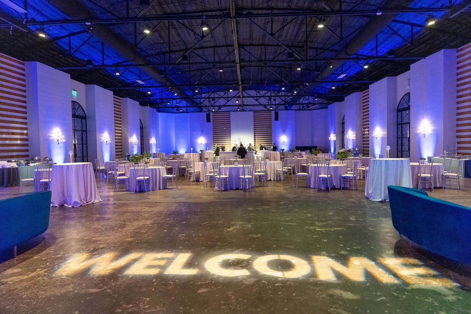 Large event space with dramatic blue uplighting and white decor elements.