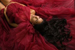 Elegant maternity portrait with flowing deep red fabric creating dramatic movement.