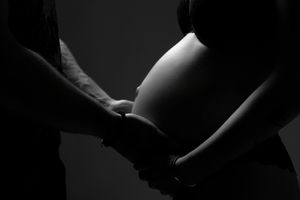 Artistic black and white silhouette of hands creating shapes against dark background.