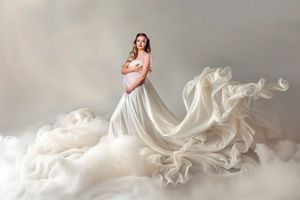 Flowing white fabric billows gracefully against a light gray background creating an ethereal and dynamic composition.