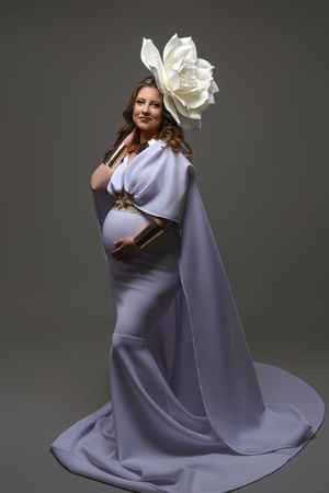 A model in a flowing lavender gown poses gracefully against a dark backdrop in a fashion photography series.