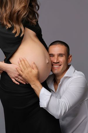 Maternity photo sequence showing tender moments between couple in black and white against grey background.
