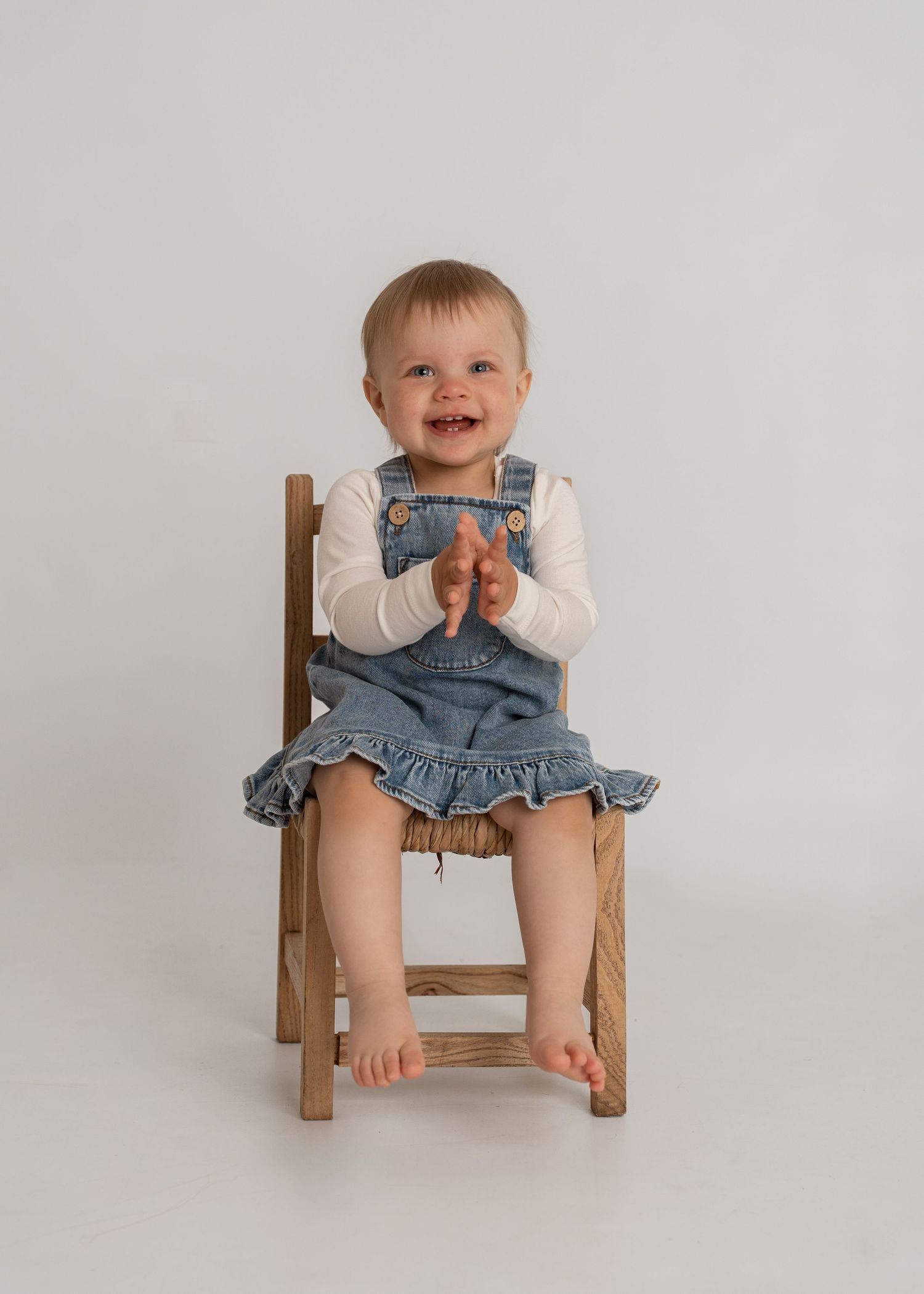 Ettårfotografi av smilende jente på stol i studio Årdal i Ryfylke