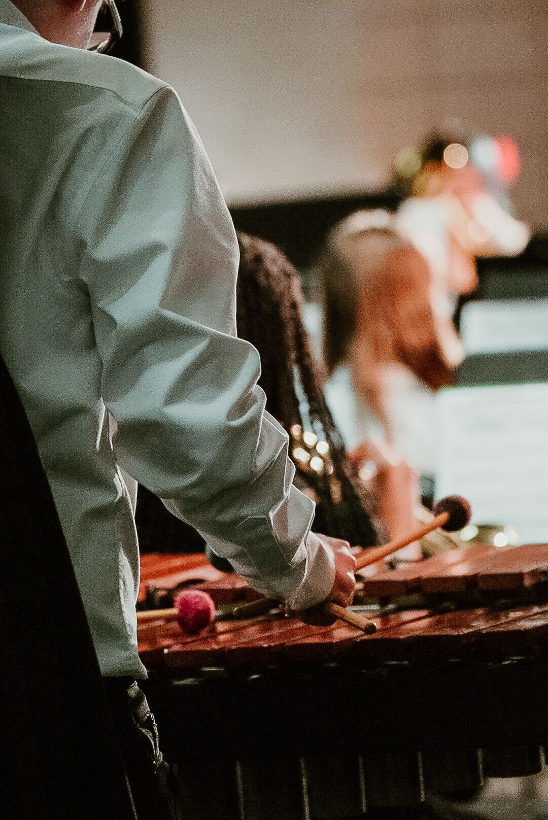 Musician plays xylophone during performance in dimly lit venue.