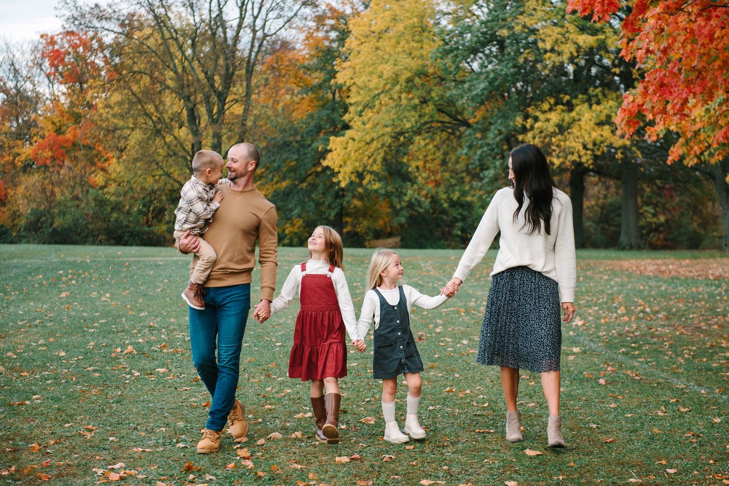 Casual family moment together in bright white modern kitchen with children sitting on countertops.