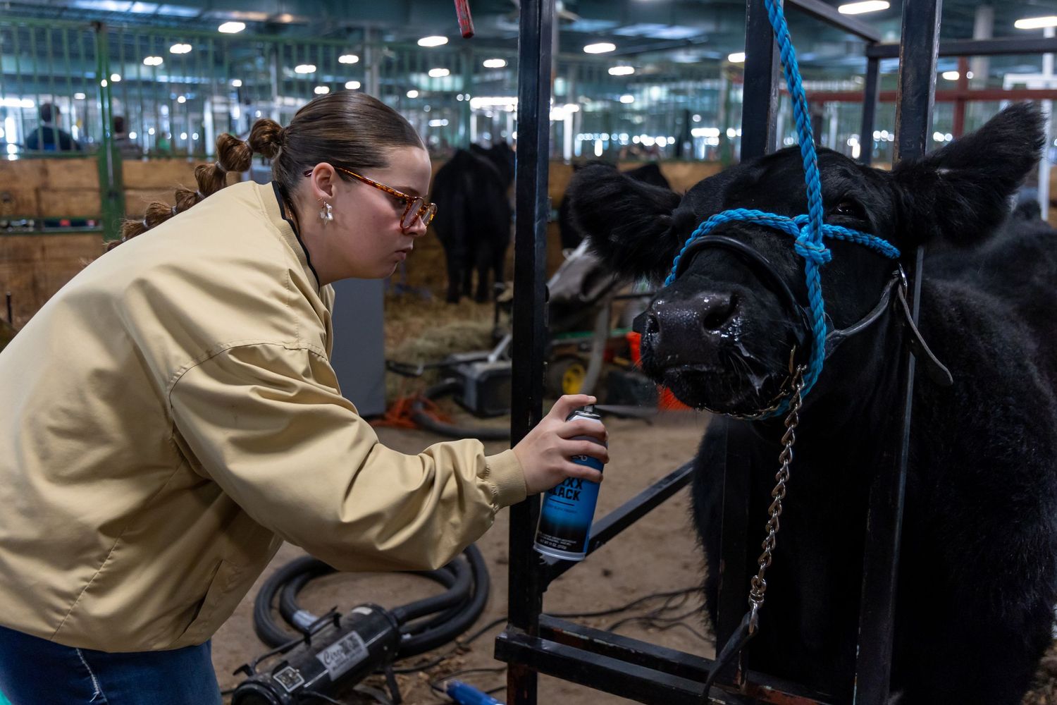 Person in yellow jacket working with equipment in industrial livestock facility.