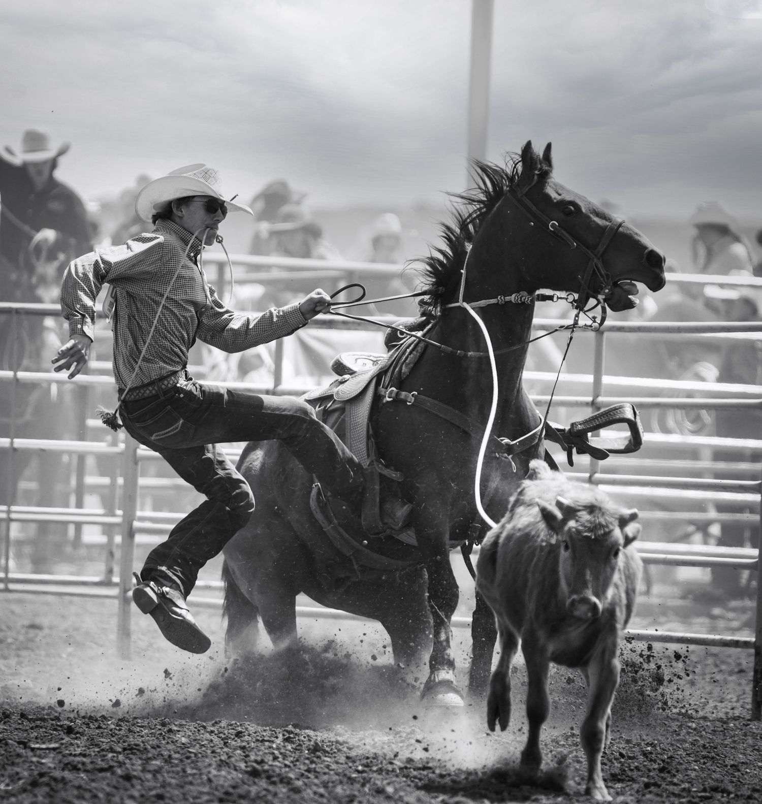 Action shot of a cowboy riding a bucking horse during a rodeo competition.