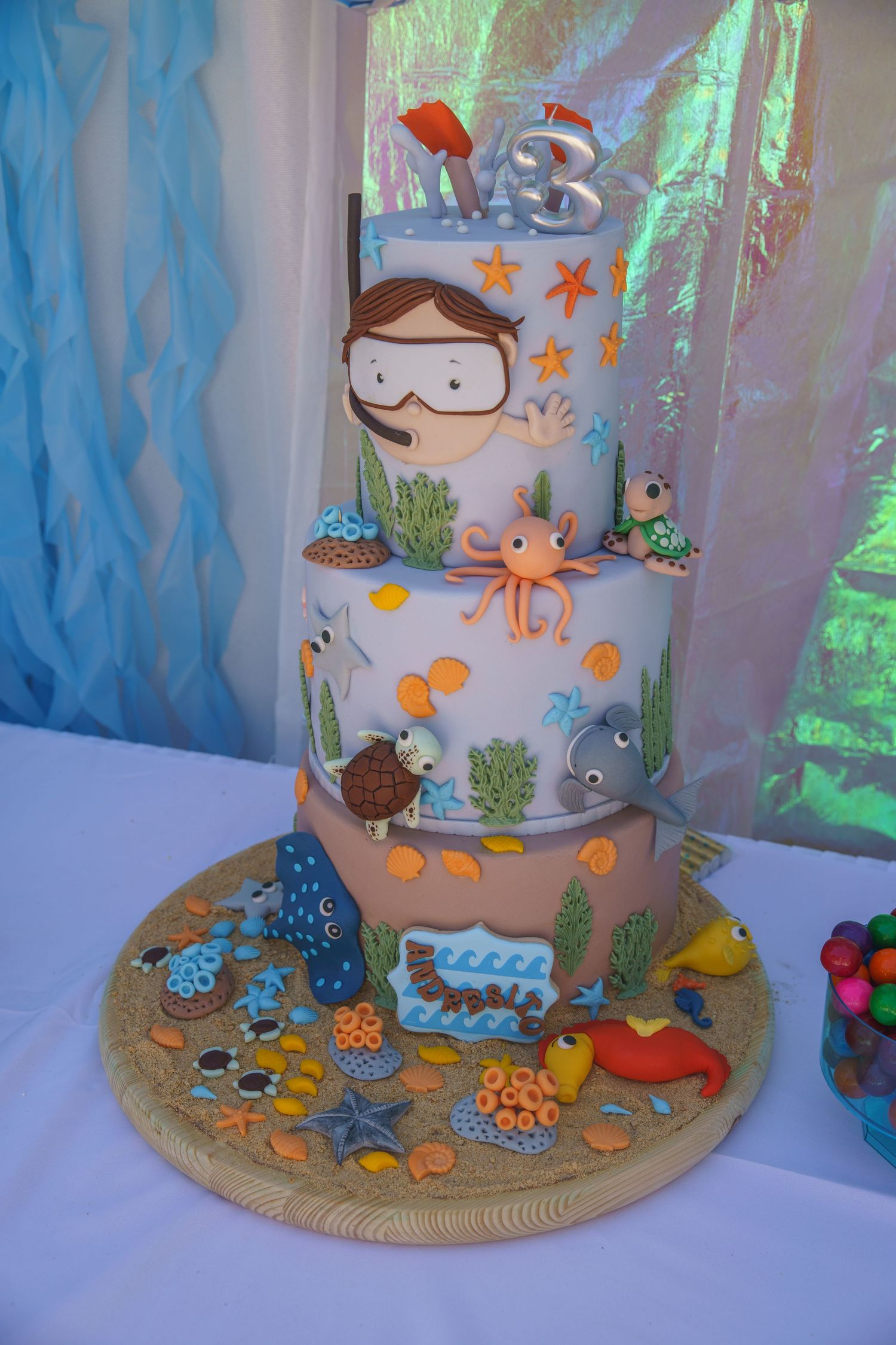 A photo showcasing the birthday party decorations of a three-tier underwater themed birthday cake.