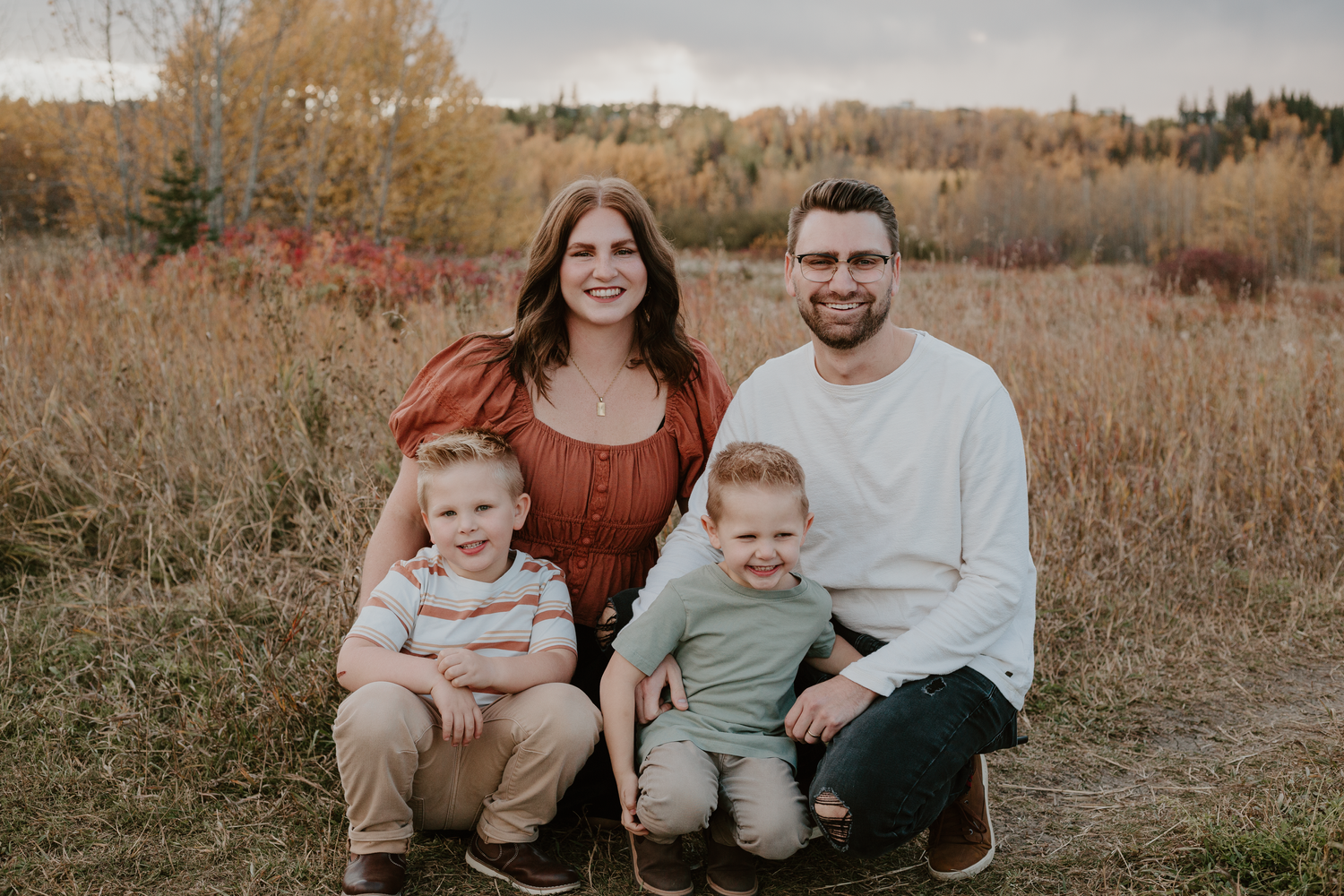 Family of four, mom, dad, and two young boys, smiling for the camera