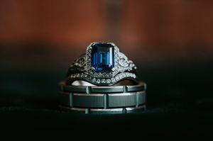 Vintage-style sapphire engagement ring stacked with diamond and tungsten wedding bands.