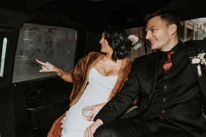Bride and groom sharing a joyful moment in a limousine on their wedding day.