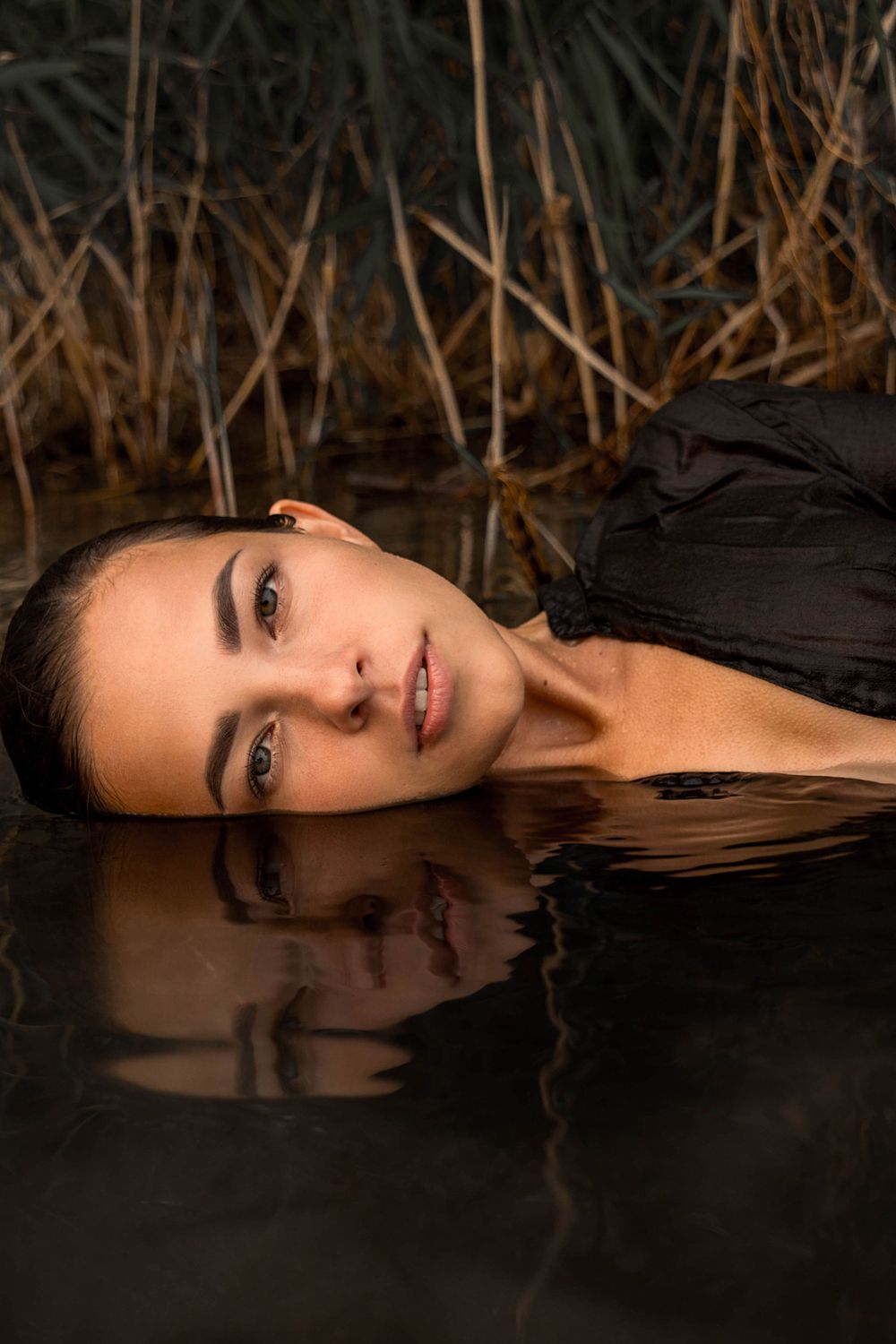A portrait of a young woman reclining in water