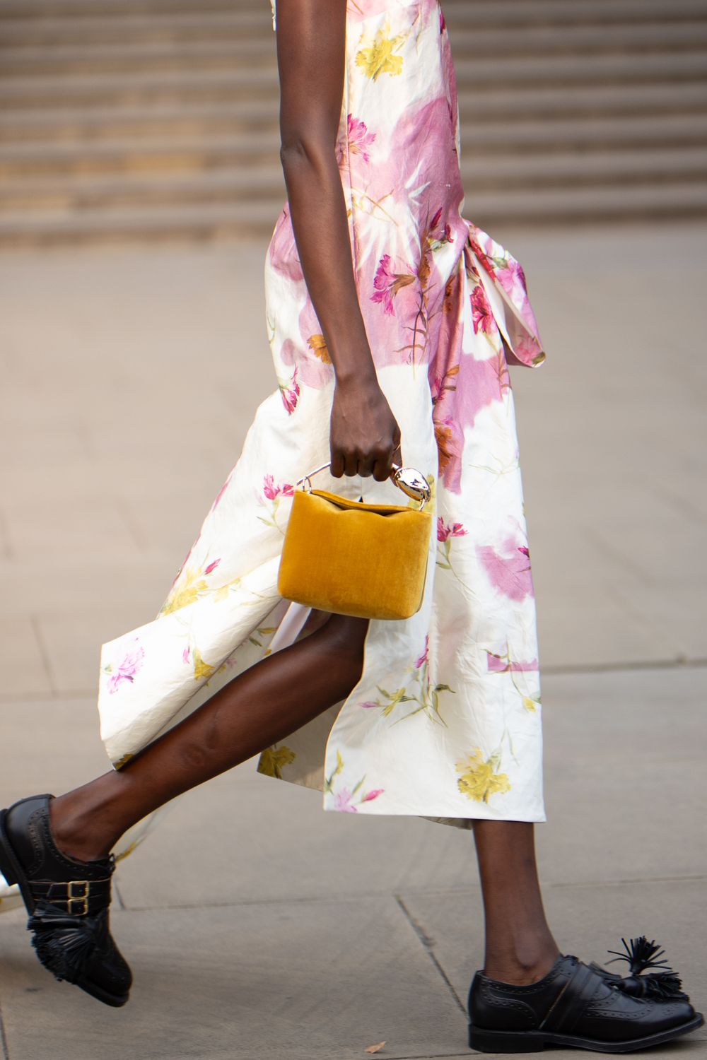 A model in a white floral dress walks on a runway  holding a yellow bag during the Erdem fashion show in London, UK.