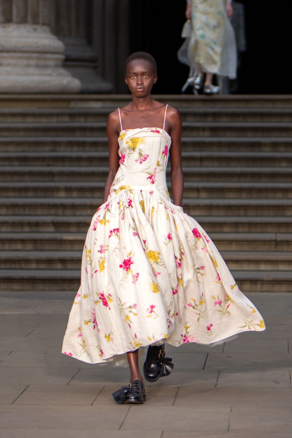 A model in a white floral dress walks on a runway during the Erdem fashion show in London, UK.
