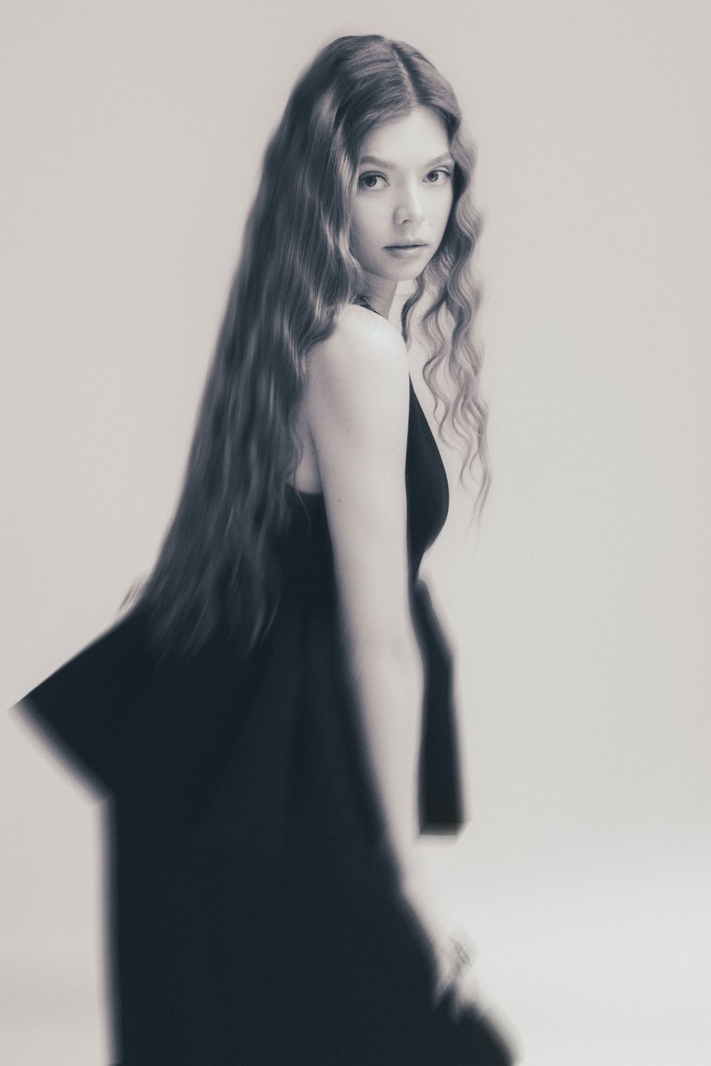 Artistic black and white portrait series showing movement and motion blur with long dark hair against light background. Cambridge