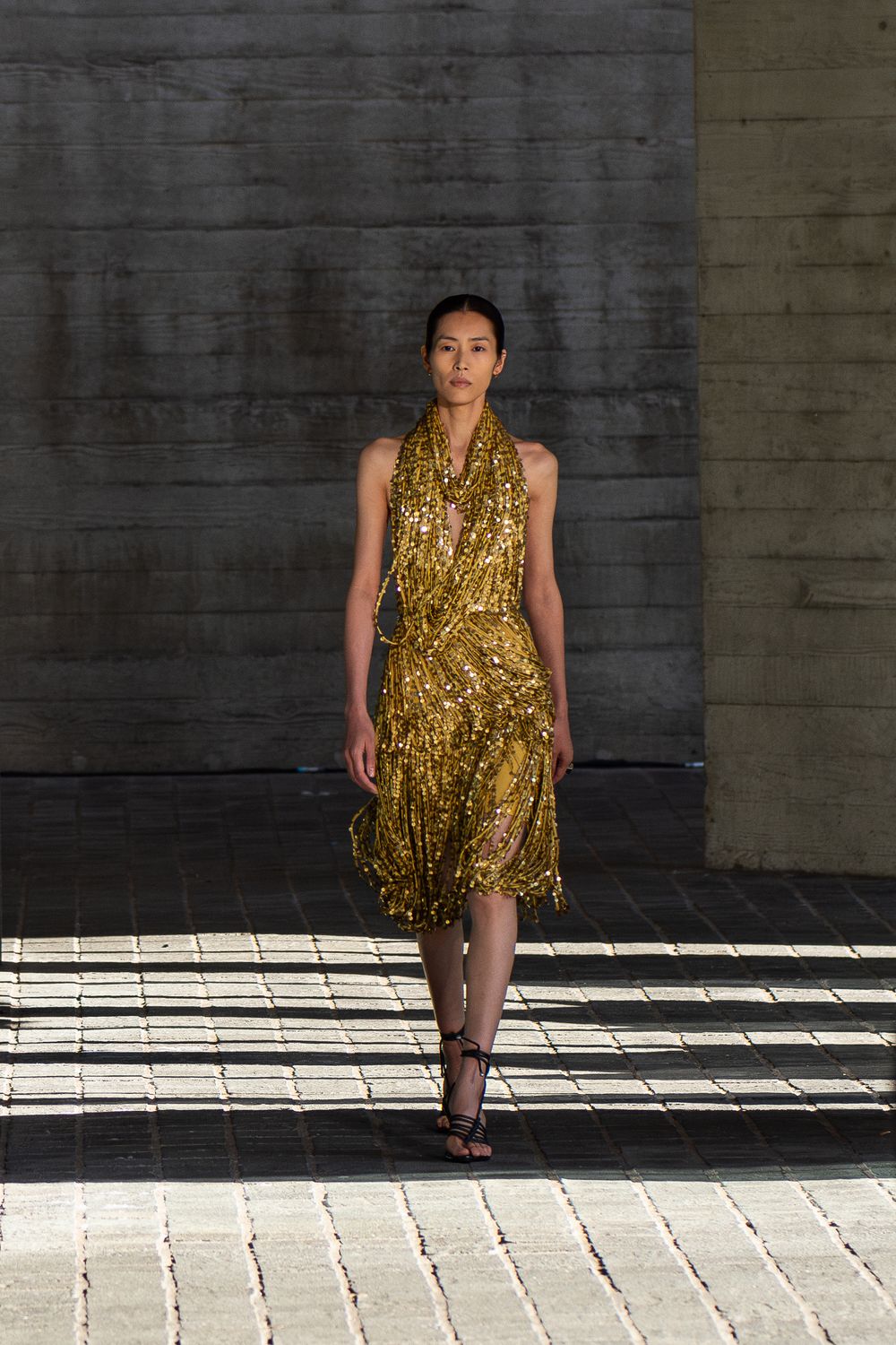 A female model in a golden dress walks on a runway during the Burberry fashion show in London, UK.