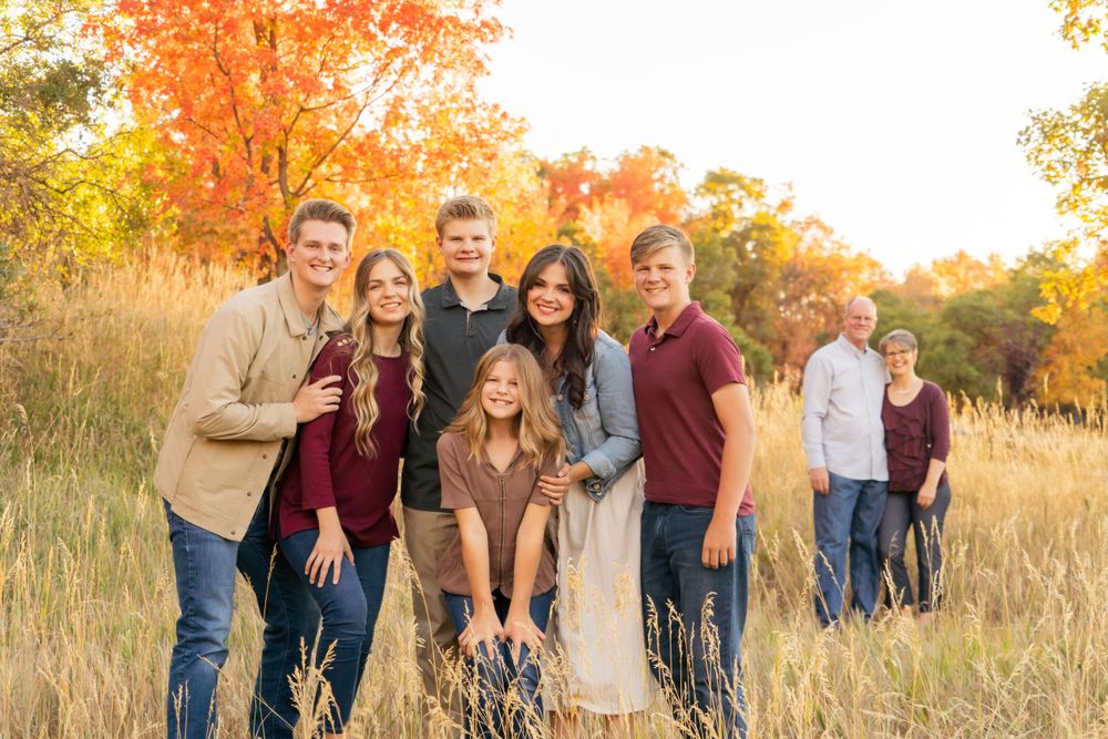 A group poses casually together in a field with warm autumn colors and golden light.