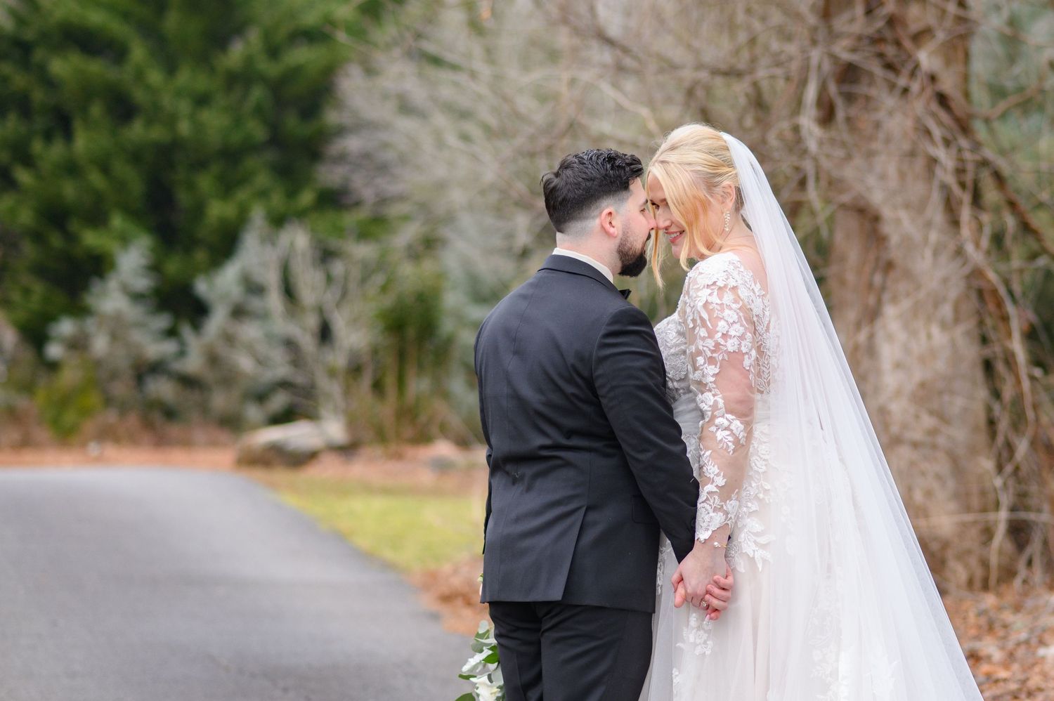 A joyful wedding couple celebrates on a winding path surrounded by evergreen trees during a winter afternoon. milton ga
