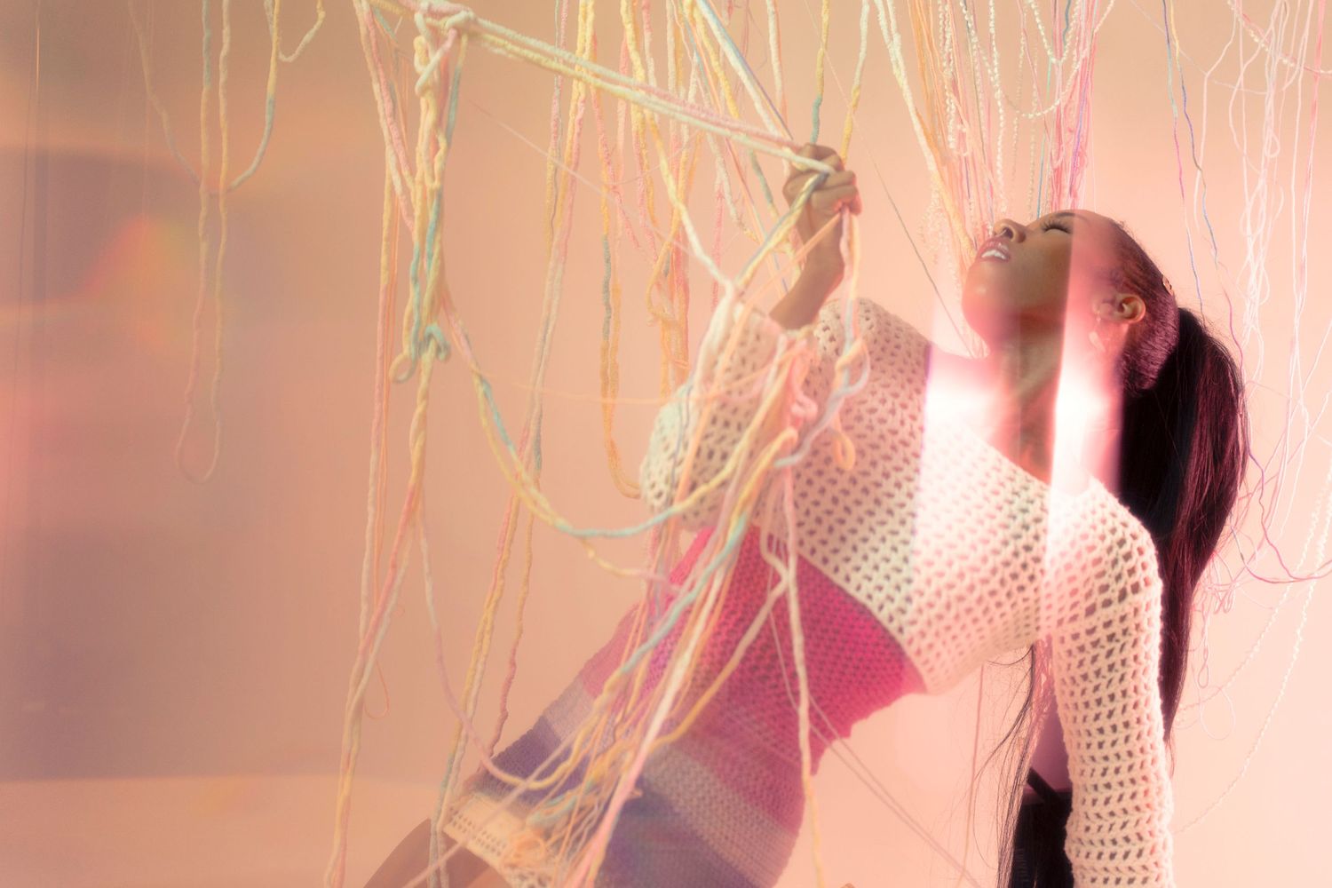 Artistic portrait with mesh fabric and soft pink lighting creating an ethereal mood.