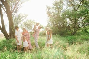 A group of people in light summer clothing dance and play in a sunlit meadow during golden hour.