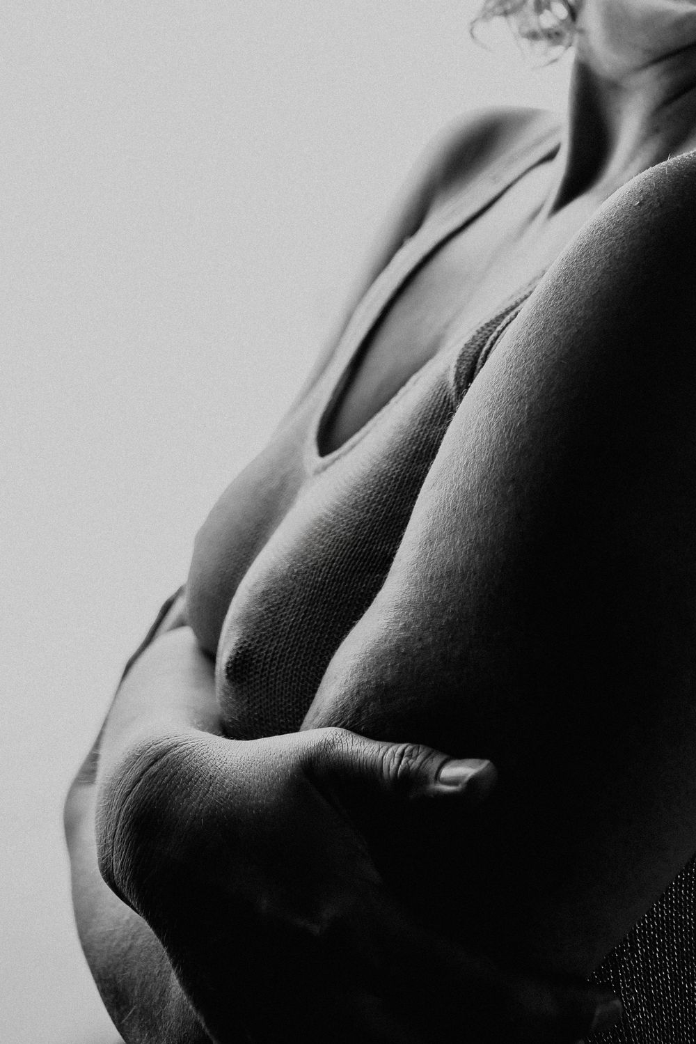 Black and white artistic photograph showing the silhouette of a torso against a light background.