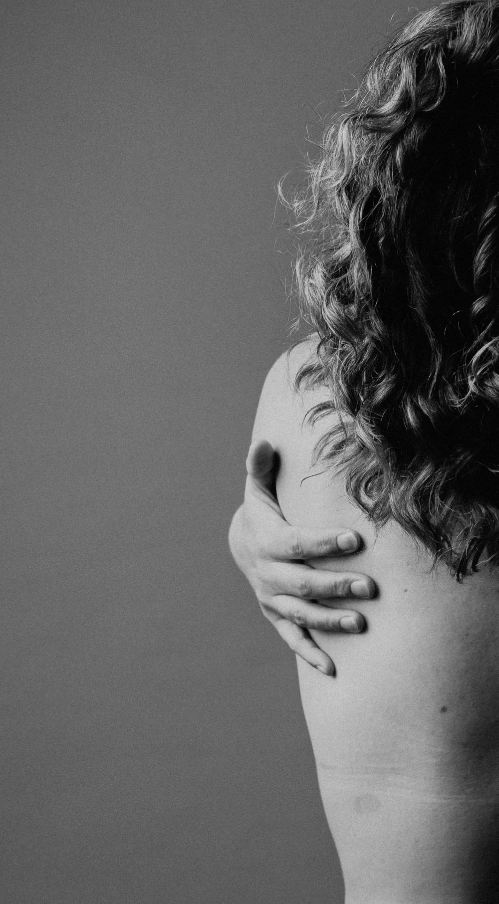 Artistic black and white close-up of a hand covering someone's face against a dark background.