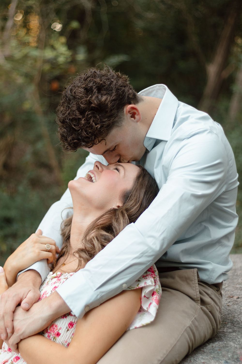 A young couple shares a romantic moment outdoors, with the man leaning in to kiss the smiling woman.