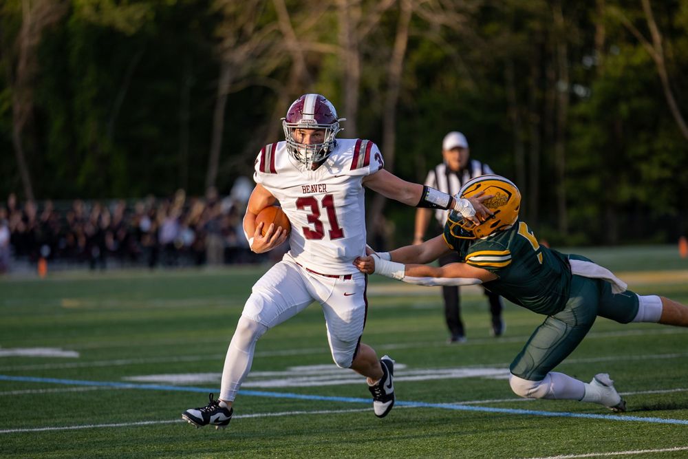 Football players collide during an intense tackle play on the grass field during a game.