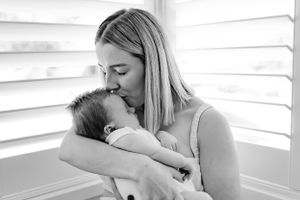 An intimate black and white portrait showing tender moments with a newborn.