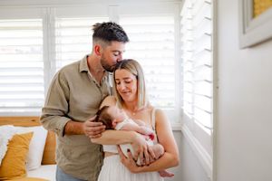 A tender family moment in a bright modern nursery with white shutters.