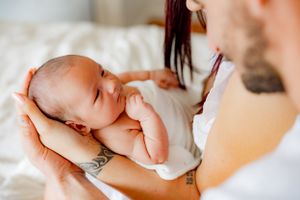 Close up of newborn baby being cradled in gentle hands.
