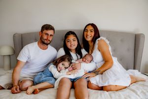 Family gathered together on gray couch for intimate portrait.