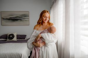 A tender moment by a bright window in a minimalist bedroom.